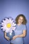 Caucasian woman holding oversized fake flower in vase.