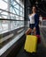 Caucasian woman on a horizontal escalator with a suitcase at the airport. A girl with pink luggage rides on a moving