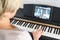 Caucasian woman learning to play piano with video lessons.