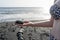 Caucasian woman in leopard bikini showing volcanic stone in black sand beach in the sunset. White woman holding wet lava rock in