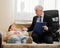 Caucasian woman lies on a couch at a reception with a psychotherapist. An elderly man works as a psychiatrist