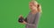 Caucasian woman looking at antique pot checking price tag on green screen