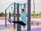 Caucasian woman in a mint sweatshirt hangs on a horizontal bar and does an exercise of the abdominal muscles on the