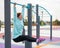 Caucasian woman in a mint sweatshirt hangs on a horizontal bar and does an exercise of the abdominal muscles on the