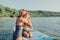 Caucasian woman mother hugging comforting crying sad son boy child on paddle sup surfboard in water.