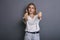 Caucasian woman in neutral casual outfit standing on a neutral grey background. Portrait with emotions: angry, pain, sickness and