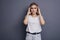 Caucasian woman in neutral casual outfit standing on a neutral grey background. Portrait with emotions: angry, pain, sickness and