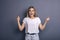 Caucasian woman in neutral casual outfit standing on a neutral grey background. Portrait with emotions: happiness, amazement, joy