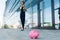 Caucasian woman in office clothes do freelance with laptop and waits colleague near the office building with pink pig