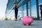 Caucasian woman in office clothes do freelance with laptop and waits colleague near the office building with pink pig