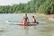 Caucasian woman parent sitting on paddle sup surfboard in water with kid child son boy.