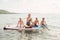 Caucasian woman parent sitting on paddle sup surfboard in water with kids children.