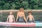 Caucasian woman parent sitting on paddle sup surfboard in water talking to kids children.