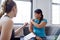 Caucasian woman physiotherapist talking to a mid-adult chinese female patient and taking notes on a tablet during a