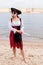 Caucasian woman in pirate costume with eye patch, cocked hat, sword on beach