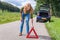 Caucasian woman placing warning triangle on rural road
