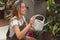 Caucasian woman is pouring water in plants. Watering houseplants in greenhouse store