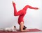 Caucasian woman practices yoga in a red bodysuit with her dog Jack Russell Terrier on a white background. The girl