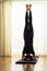 Caucasian Woman Practicing Yoga Exercise Indoors At Bright Afternoon. Sitting in Shirshasana Pose During Solitude Meditation