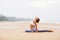 Caucasian woman practicing yoga at seashore of tropic ocean