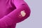 Caucasian woman in purple clothes with holes on elbow close-up. Gray background