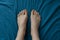 Caucasian woman`s feet on blue sheets.