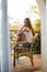 Caucasian woman sitting and relaxing on balcony of the hotel with idyllic sea scenery, looking at sea background.