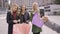 Caucasian woman taking photoes of her three friends with shopping bags. Four fashion women resting after shopping. Girls