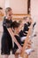 Caucasian woman teaches little girls ballet at the barre. Vertical photo.