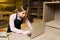 Caucasian woman typing on a laptop inside her woodshop