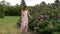 Caucasian Woman Walking Near The Blossoming Bushes With Pink Roses Flowers