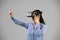 Caucasian woman wearing a Virtual Reality headset on grey background.