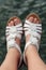 Caucasian Woman Wearing White Leather Strap Sandals with Flower Decor, Feet in a Closeup