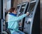 Caucasian woman in a wheelchair buys a train ticket using a mobile phone at a self-service checkout.