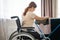 Caucasian woman in a wheelchair hangs wet laundry on a dryer.