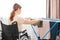 Caucasian woman in a wheelchair hangs wet laundry on a dryer.