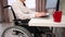 Caucasian woman in a wheelchair typing with a laptop from home. Remote work for people with disabilities.