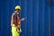 Caucasian worker in safety vest reflective with Safety helmet holding tablet and talking to radio reciever to checked about his