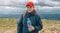 Caucasian young blonde girl shows water from plastic bottle. mountain background.