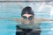 Caucasian young male swimmer wearing goggles swimming indoors in a pool