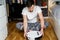 Caucasian young man in christmas pajamas doing vacuum cleaner robot maintenance. Male in winter patterned sleepwear and red socks