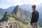 Caucasian young man looking at the amazing Machu Picchu landscape. Peru, South America