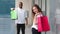 Caucasian young millennial girl woman stands near blurred African American guy man hold shopping bags smiling
