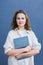 Caucasian young woman freelancer, businesswoman or student standing with computer at the wall.