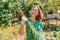 A Caucasian young woman joyfully holds a bunch of carrots collected from the garden.Vegetation in the background.Concept of