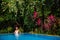 Caucasican woman rests in blue pool in tropics