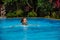 Caucasican woman rests in blue pool in tropics