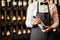 Caucasin elegant male sommelier with wine bottle near rack at wine store