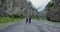 The Caucasus. A couple of hikers stands on road among rocks and looks at camera