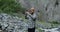The Caucasus. Young man takes pictures on phone standing near a mountain river